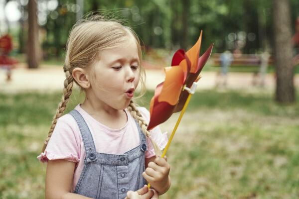 Cute little girl blowing in the windmill in the windmill - SKIDamarink KIDs girl blowing pinwheel for self regulation