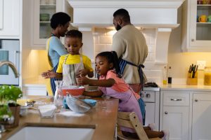 African american siblings mixing batter in bowl on kitchen island and parents cooking in background