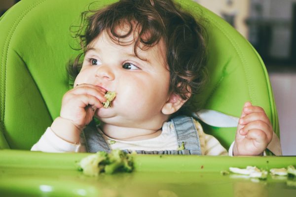 Baby eating food in her green highchair - SKIDamarink KIDs Baby eating food in her green highchair