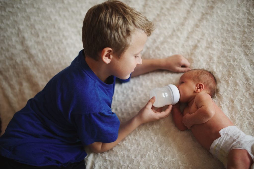 boy feeding newborn baby with bottle of milk - SKIDamarink KIDs boy feeding newborn baby with bottle of milk