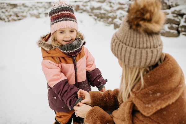 Child smiling in snow playing with an adult - SKIDamarink KIDs Child smiling in snow playing with an adult