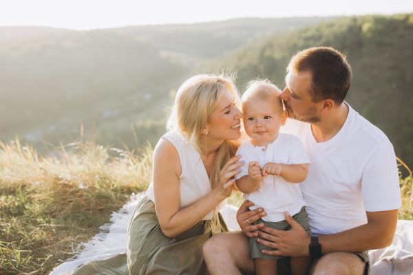 Loving Family Enjoying Outdoor Picnic with Young Child in Sunny Countryside Setting - SKIDamarink KIDs Loving Family Enjoying Outdoor Picnic with Young Child in Sunny Countryside Setting