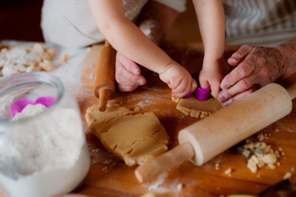 Midsection of grandmother with small toddler boy making cakes at home - SKIDamarink KIDs Midsection of grandmother with small toddler boy making cakes at home.