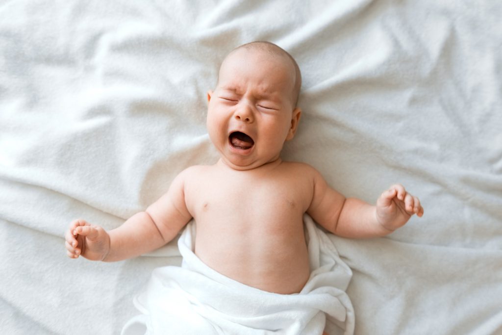 Newborn crying baby boy New born child tired and hungry in bed under blanket Children cry - SKIDamarink KIDs Newborn crying baby boy. New born child tired and hungry in bed under blanket. Children cry.