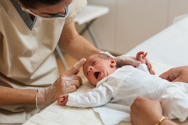Physiotherapist evaluating the asymmetric tonic reflex in a newborn baby - SKIDamarink KIDs Physiotherapist evaluating the asymmetric tonic reflex in a newborn baby