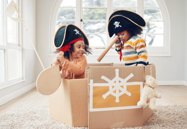Playing, box ship and pirate kids role play, fantasy imagine or pretend as yacht captain in cardboa