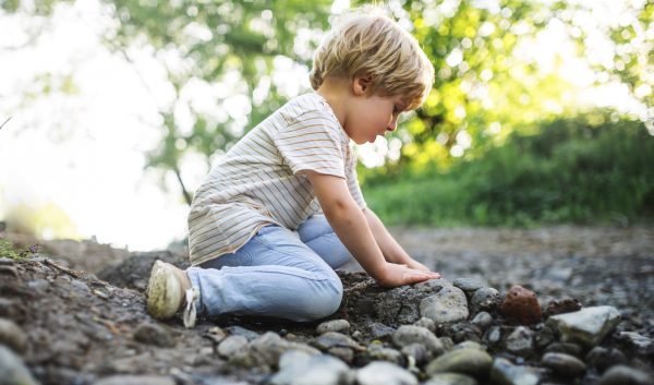Side view of small boy playing with rocks and mud in nature - SKIDamarink KIDs Side view of small boy playing with rocks and mud in nature- outdoor play