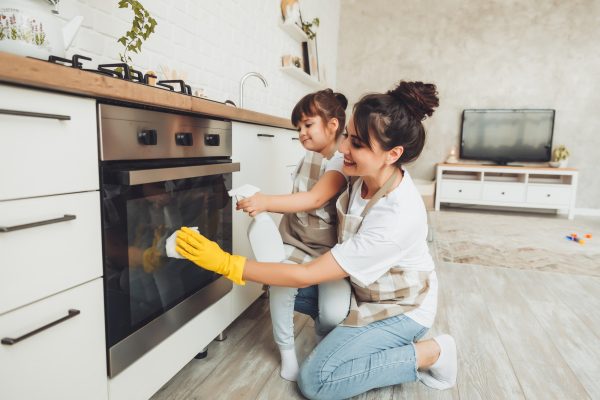 A little girl and her mother are cleaning the kitchenwoman and child wipe the oven in the kitchen - SKIDamarink KIDs A little girl and her mother are cleaning the kitchen.woman and child wipe the oven in the kitchen