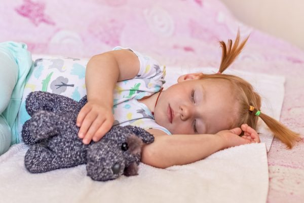 A little girl toddler is sleeping on a bed with toys cuddled Childhood - SKIDamarink KIDs A little girl toddler is sleeping on a bed with toys cuddled . Childhood.