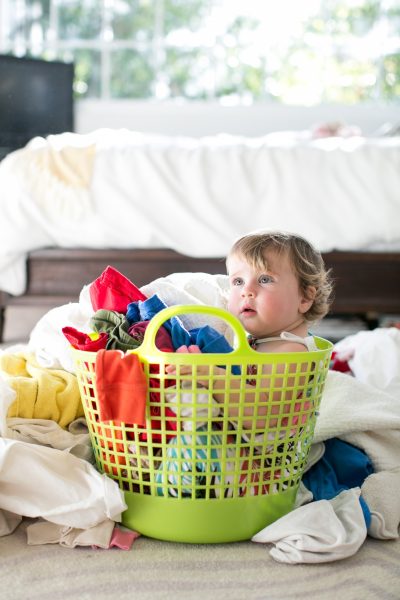 Female toddler sitting in basket amongst laundry - SKIDamarink KIDs Female toddler sitting in basket amongst laundry