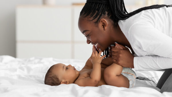 African American mom playing in bed with her black baby - SKIDamarink KIDs infant face-to-face interaction,baby positioning for bonding